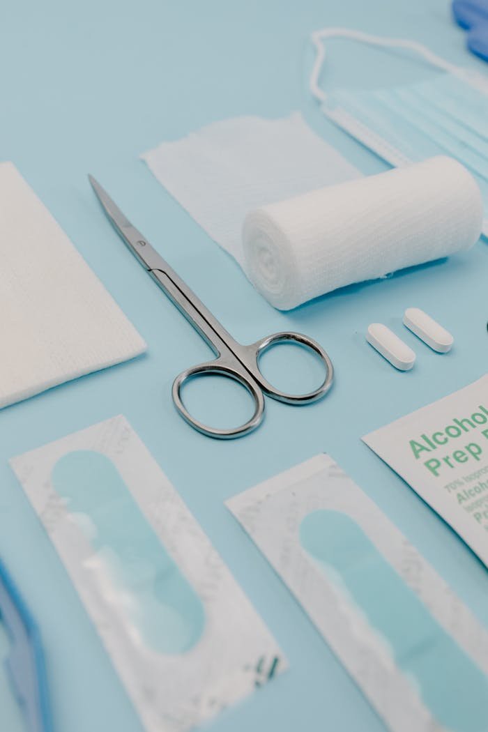 Close-up of medical supplies on a blue background, featuring bandages, pills, and scissors.